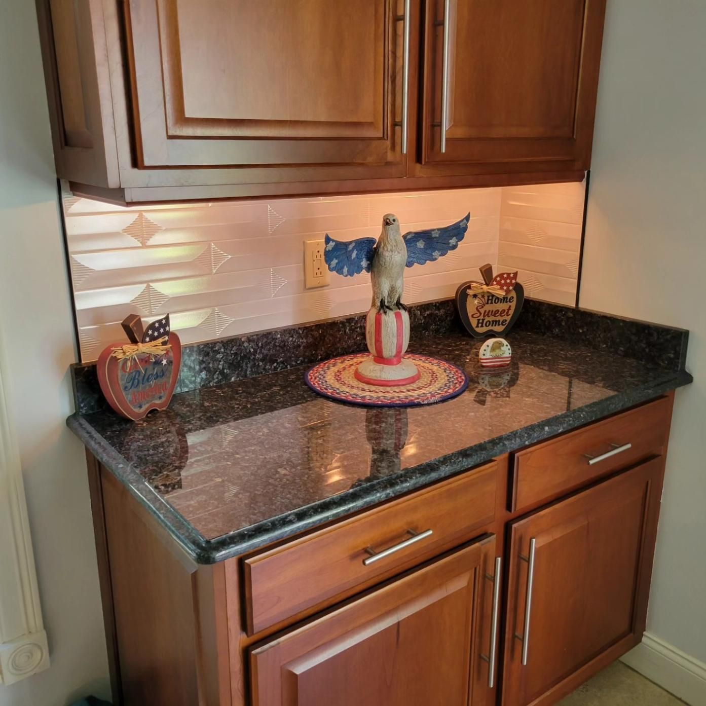Kitchen corner counter with dark granite, wooden cabinets, and decorative bird figurines.