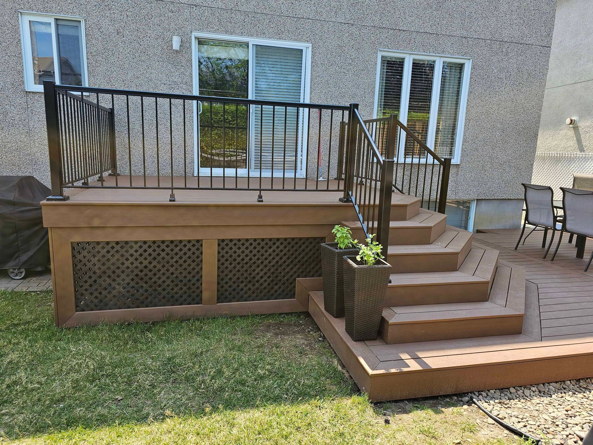Une terrasse avec des escaliers qui y mènent se trouve dans l'arrière-cour d'une maison.
