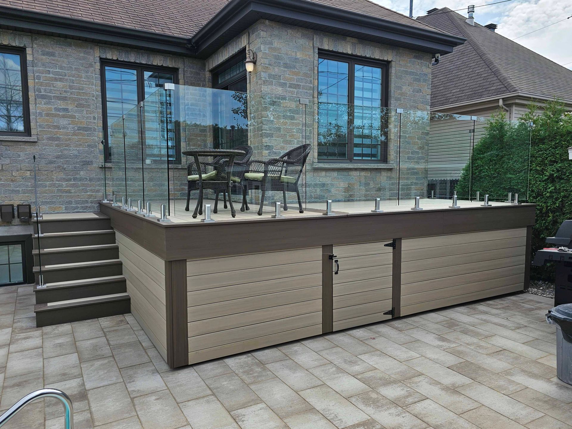 Une grande terrasse avec une table et des chaises devant une maison.