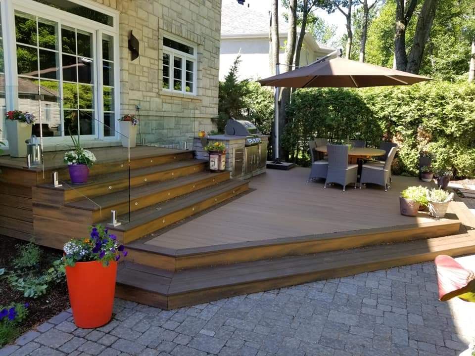 Une terrasse avec une table, des chaises et un parasol dans l'arrière-cour d'une maison.