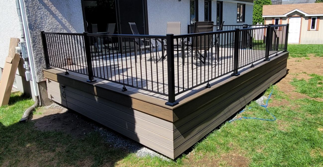 Une terrasse avec une balustrade en métal devant une maison.