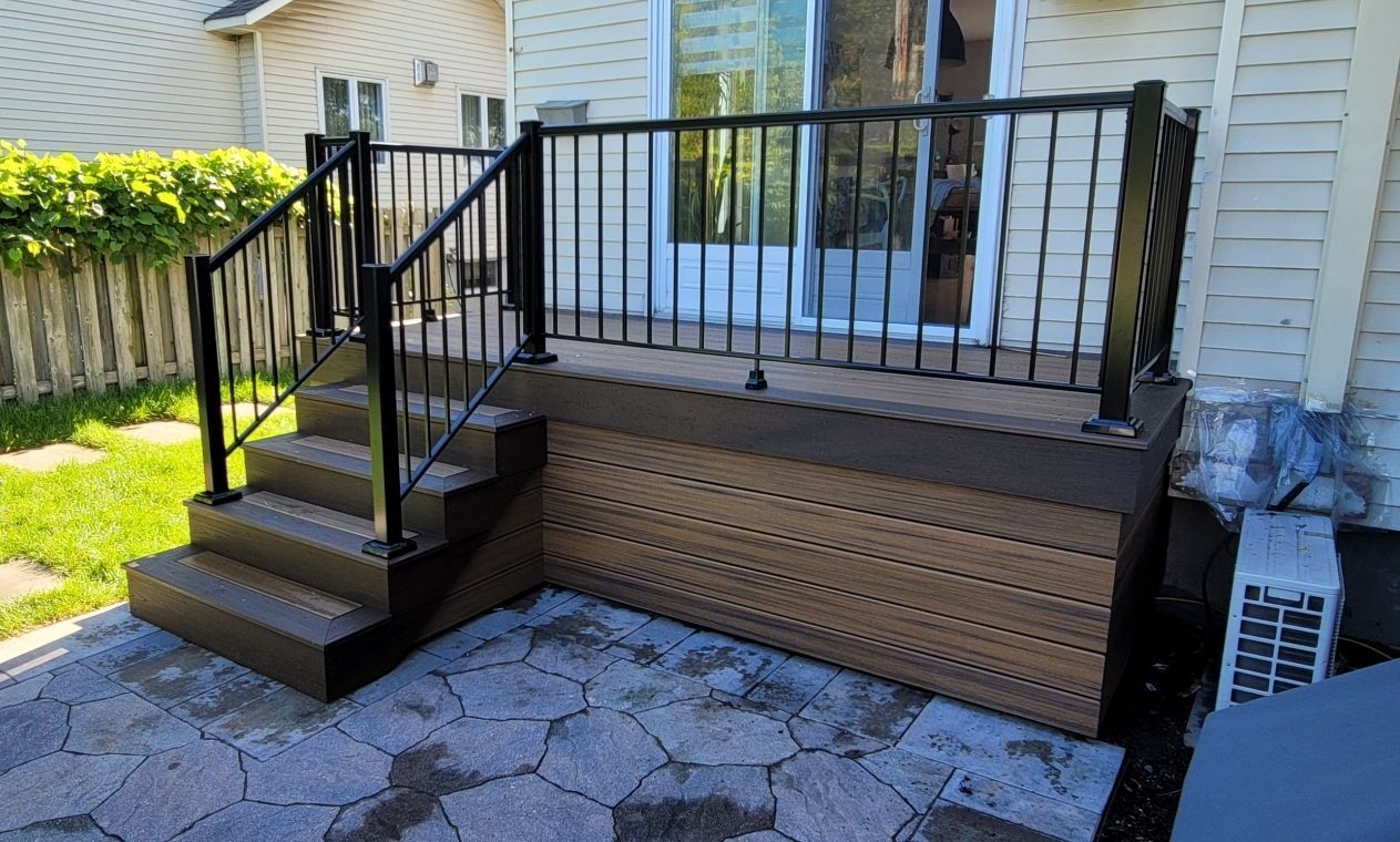 Une terrasse avec des escaliers et une balustrade devant une maison.