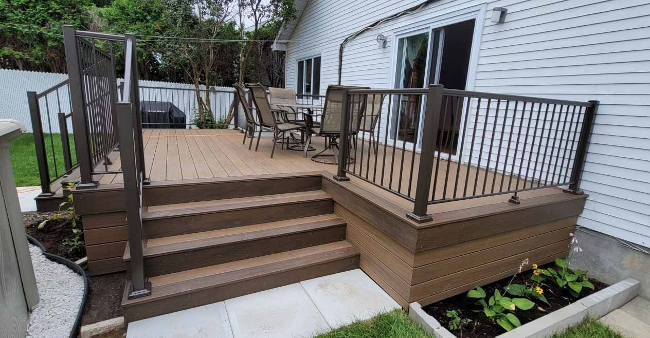 Une terrasse avec des escaliers et une rampe en métal devant une maison.