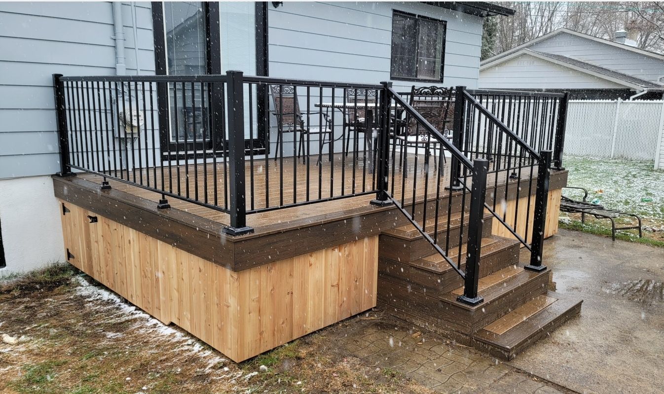 Une terrasse avec une balustrade en métal et des escaliers à côté d'une maison.