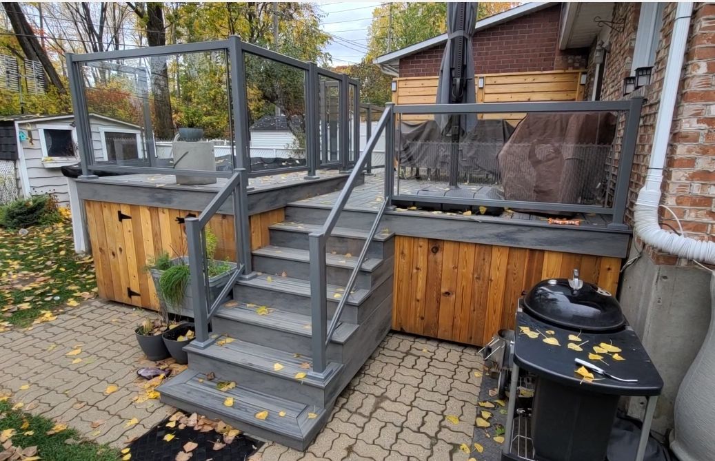 Une terrasse avec des escaliers et un barbecue devant une maison.