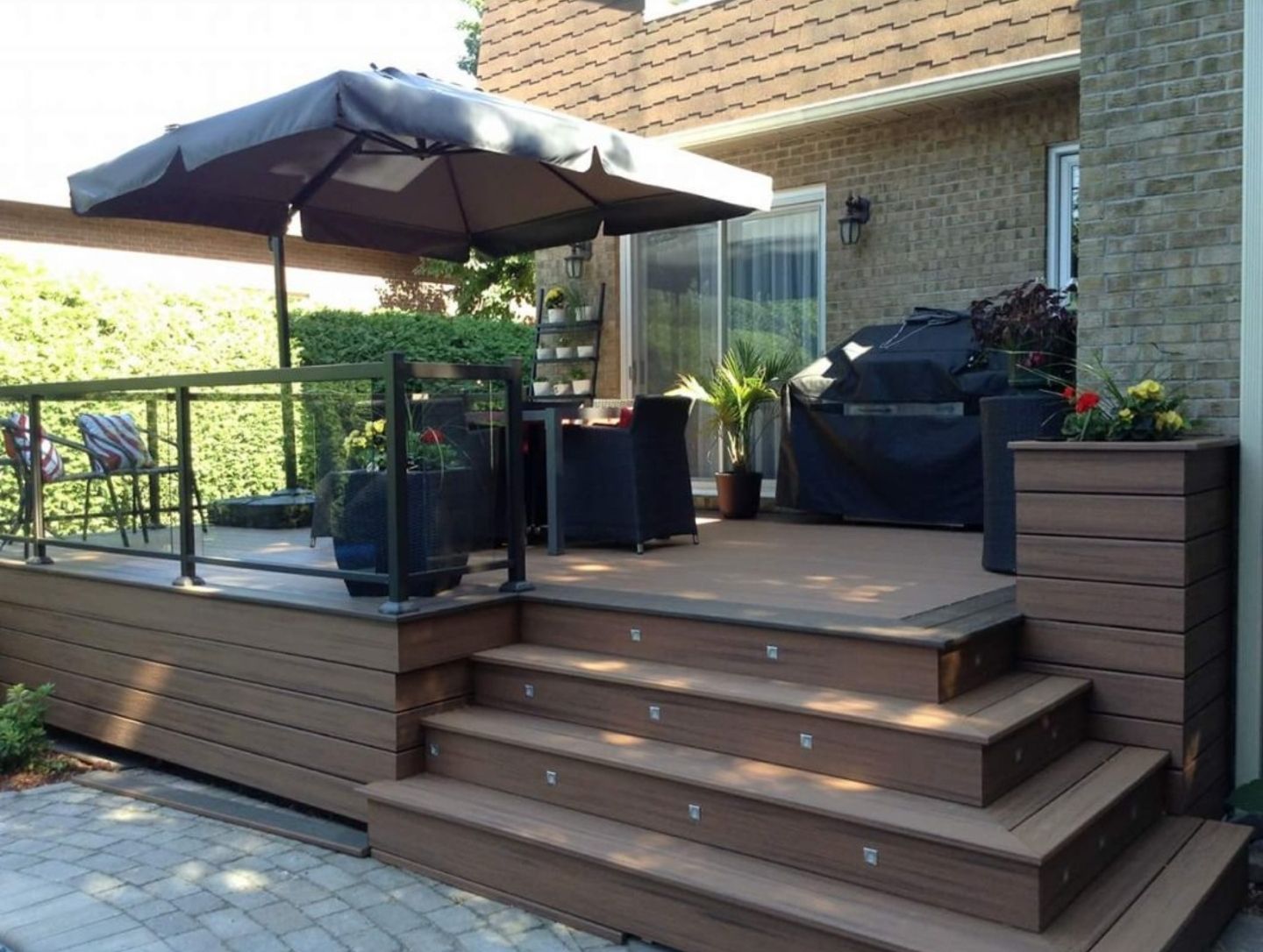Une terrasse avec des escaliers et un grand parasol