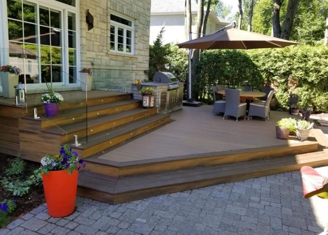 Une terrasse avec une table, des chaises et un parasol dans l'arrière-cour d'une maison.