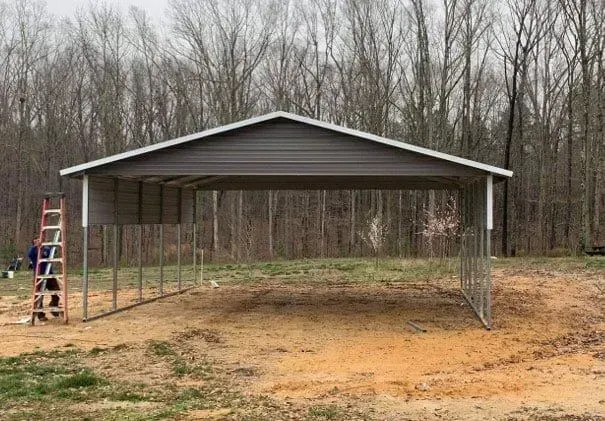 A carport is being built in the middle of a dirt field.