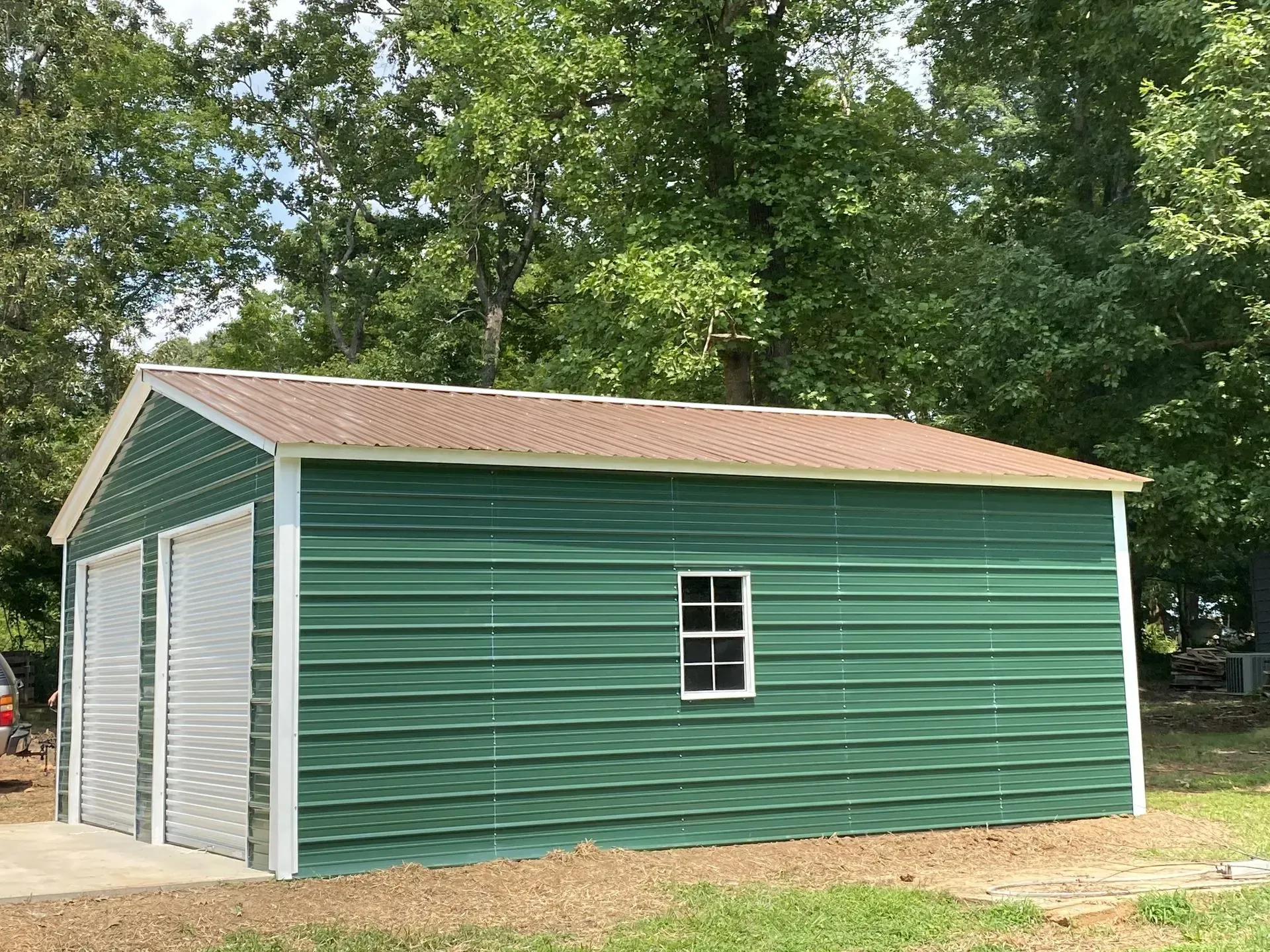 A green garage with a window and a red roof