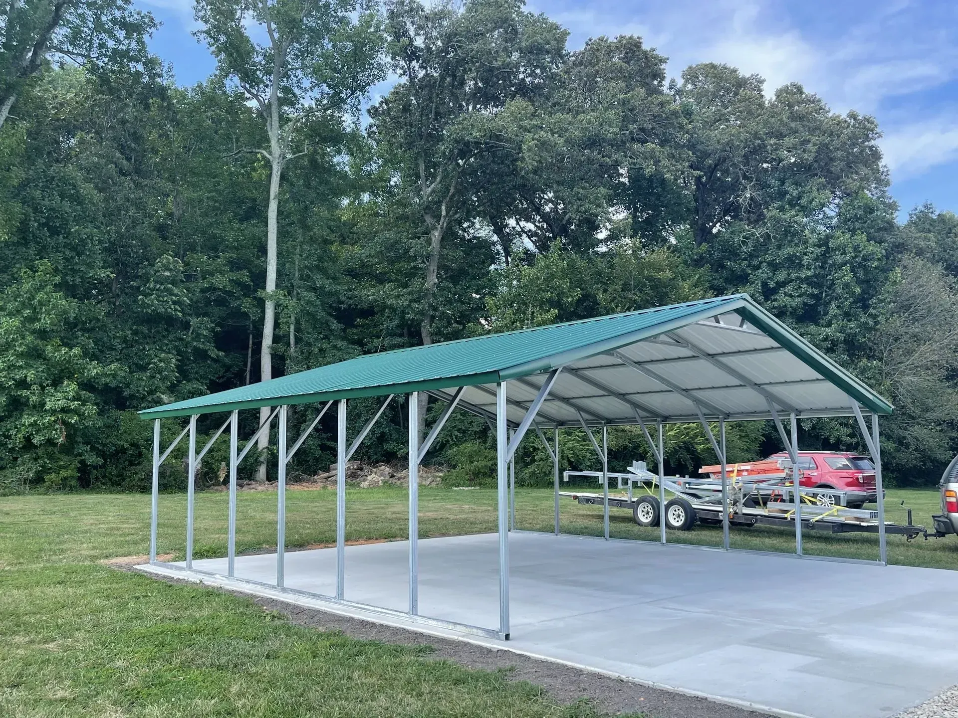 A carport with a green roof and a boat in it.