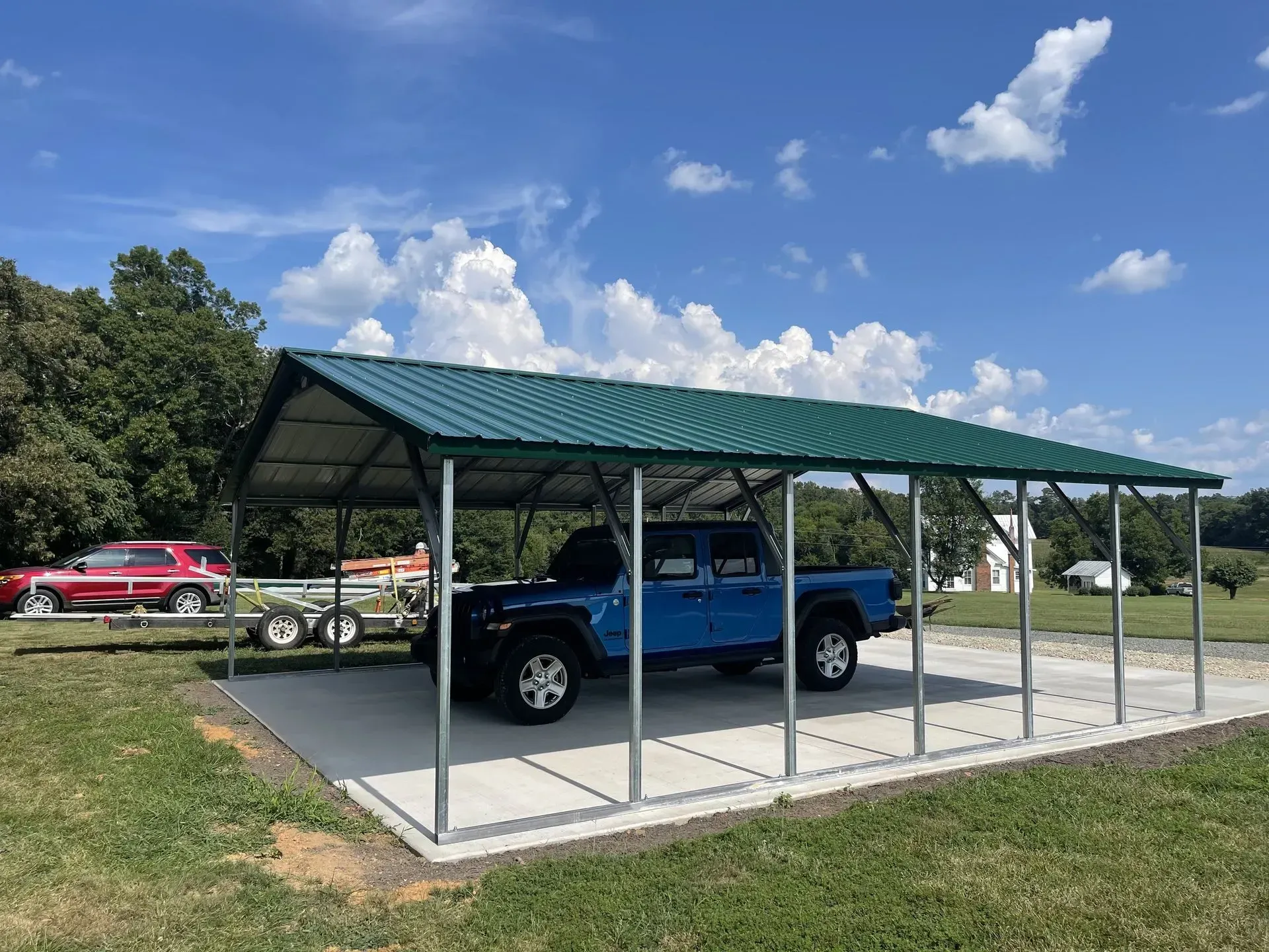 A blue truck is parked under a green carport.