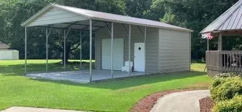 A large metal building is sitting in the middle of a lush green field.