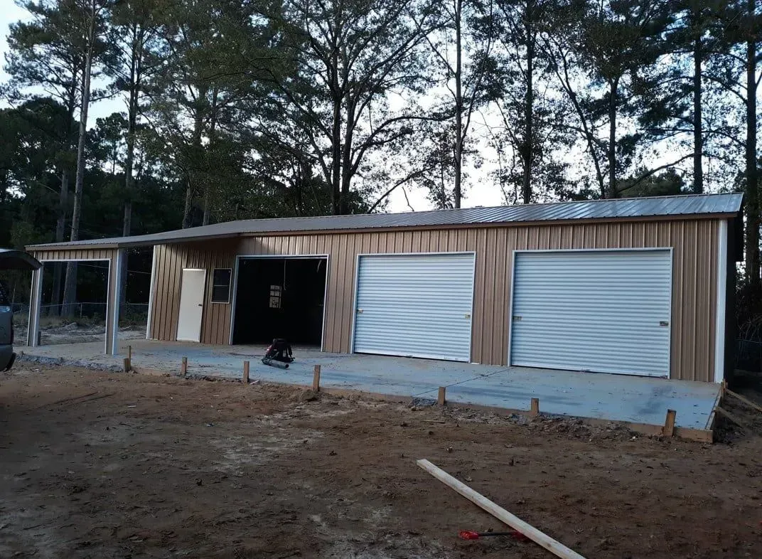 A garage with two garage doors is being built in the middle of a dirt field.
