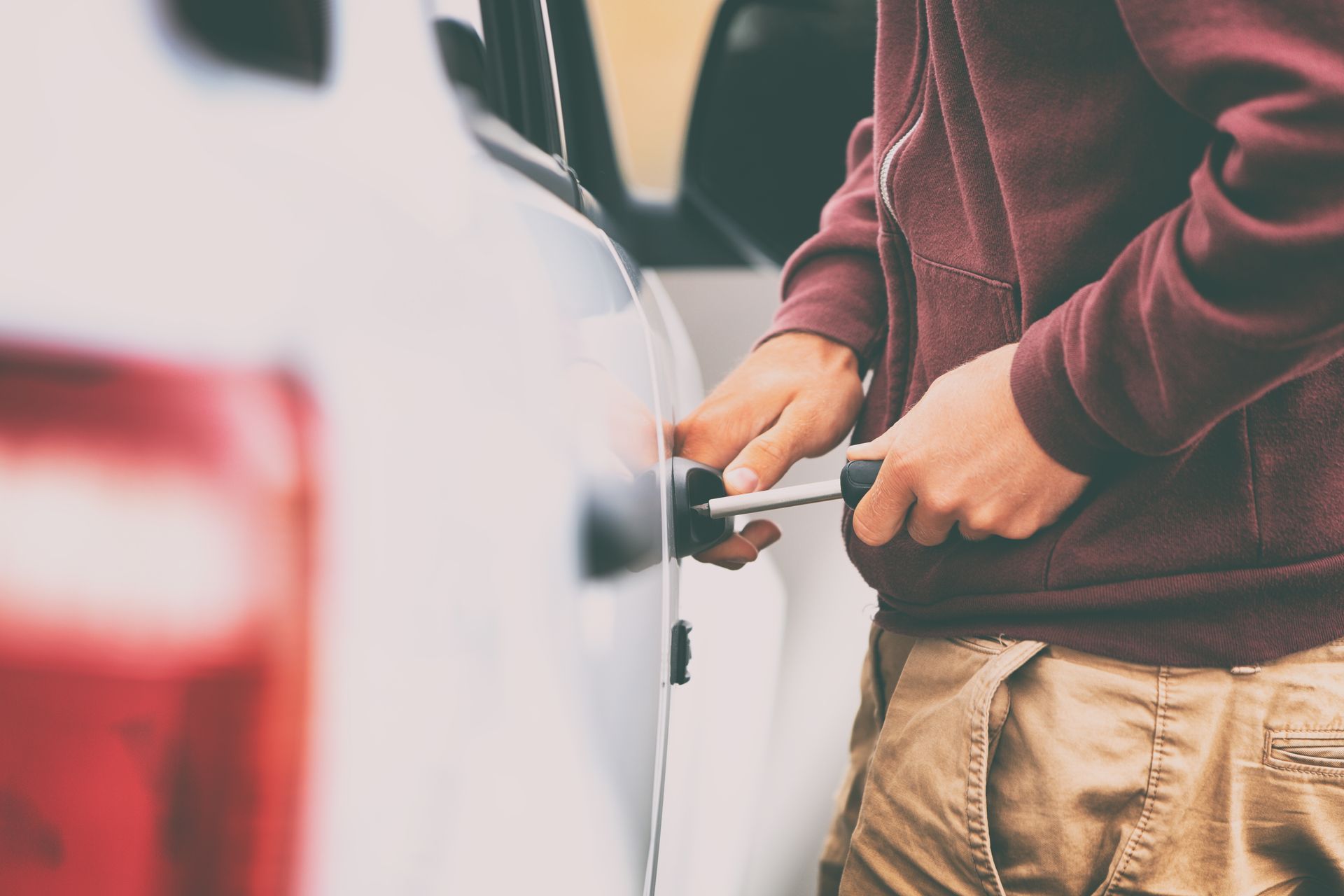 person in a red hoodie stealing a car