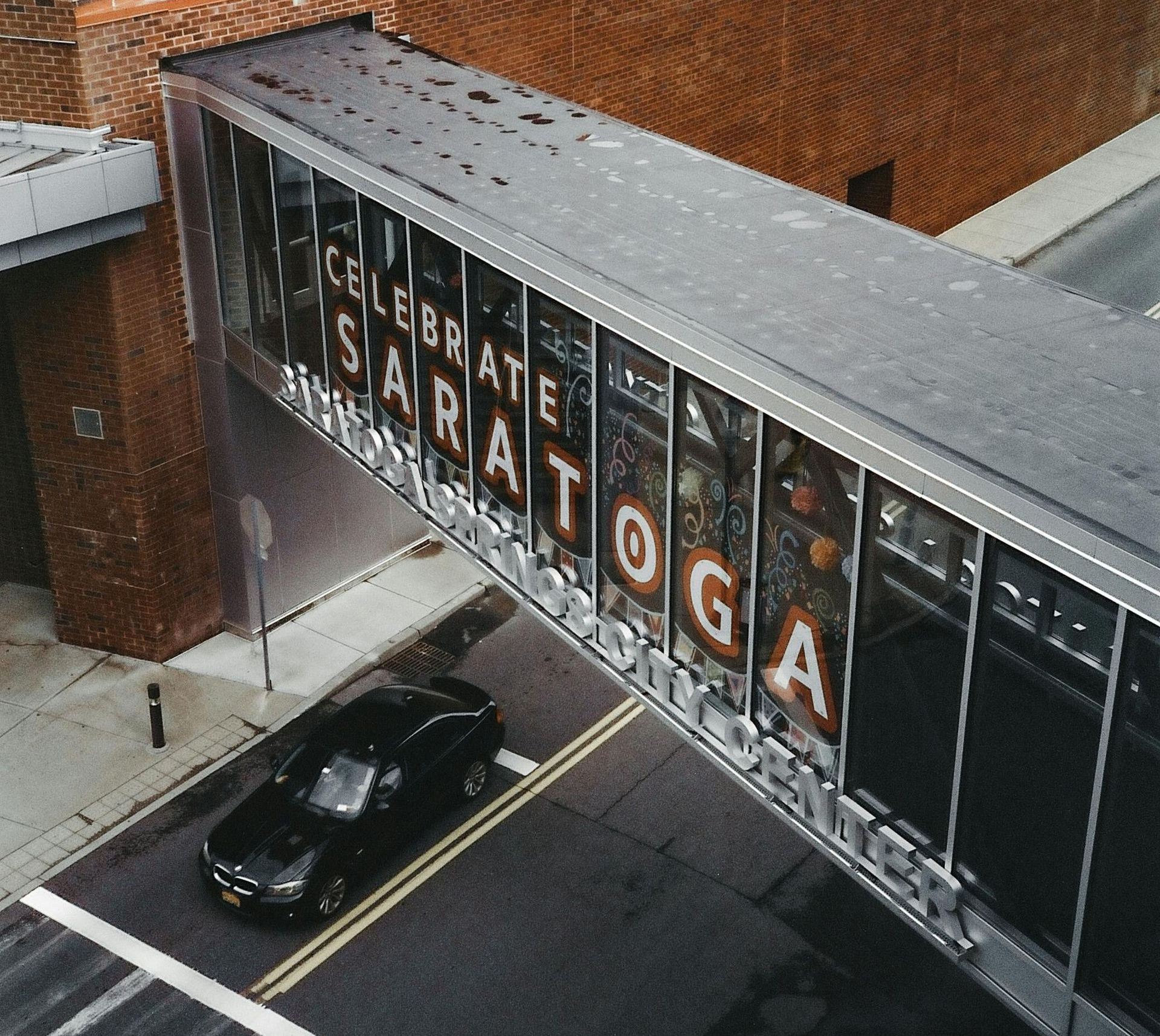 A black car travels under a skywalk that reads 