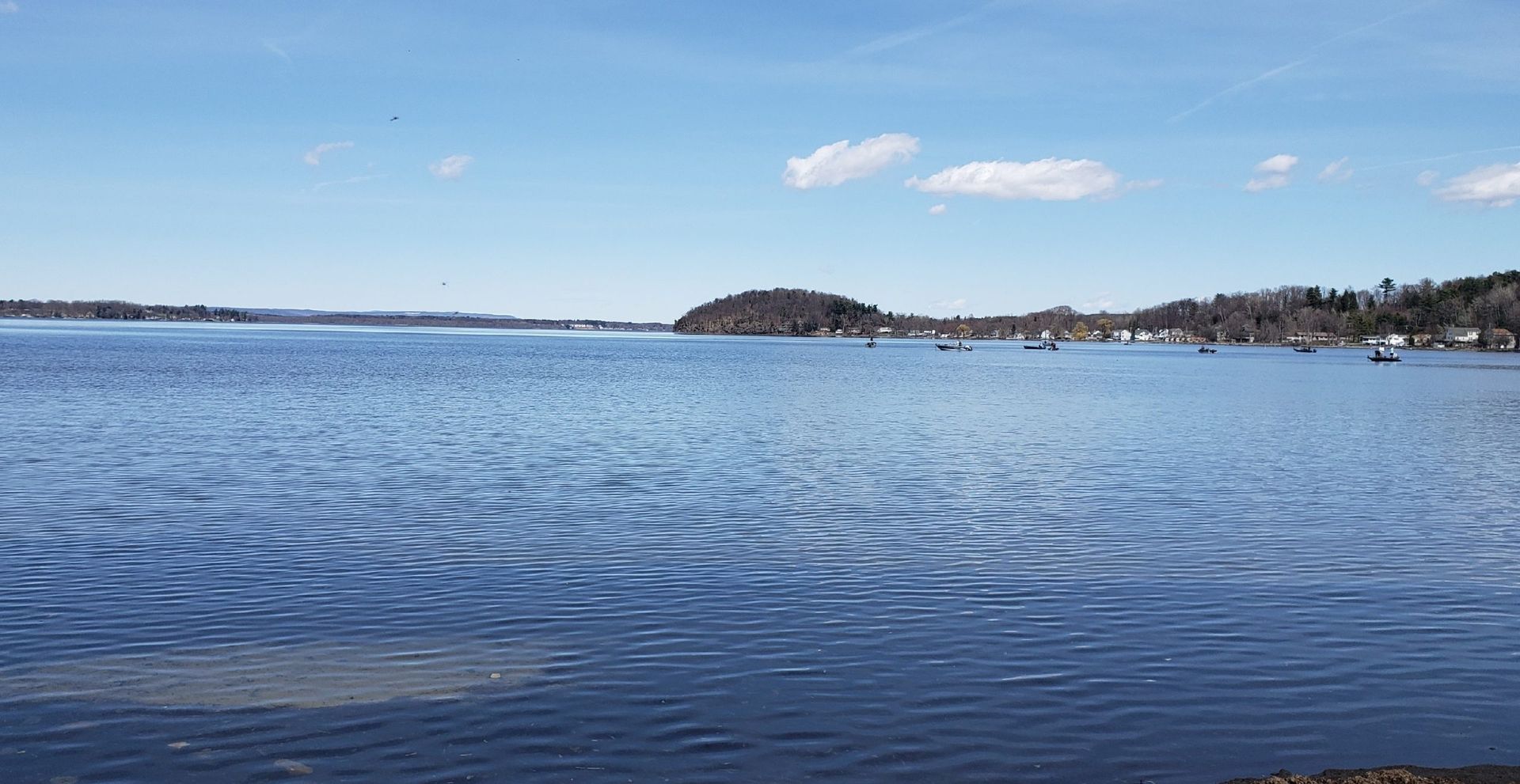 Blue water expanse with island under blue sky.