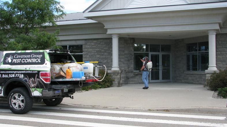 A truck is parked in front of a building that says pest control