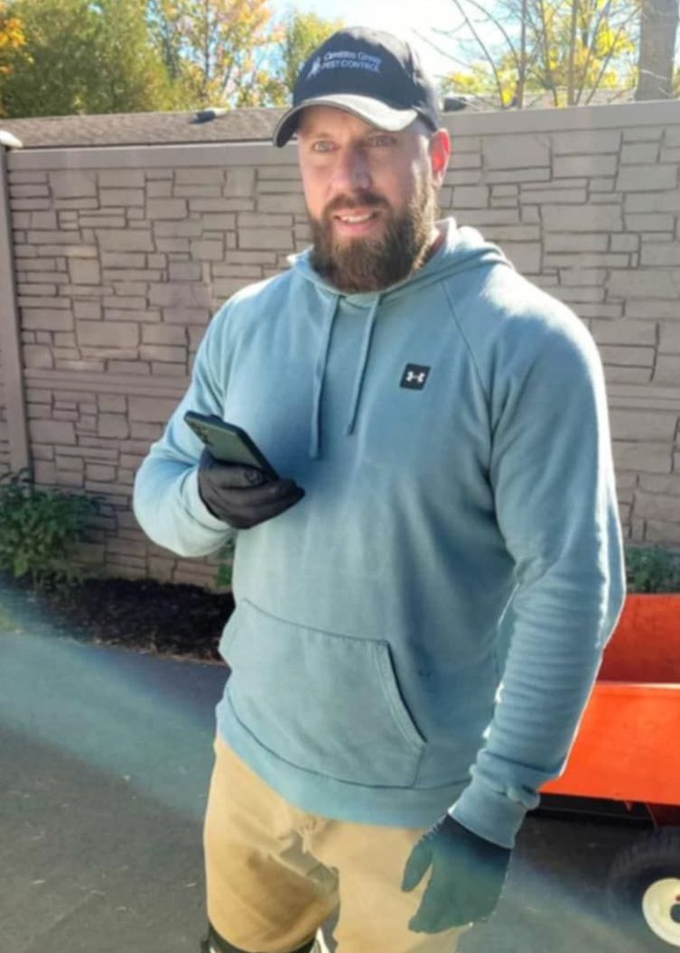 A man wearing a hoodie and a hat is holding a cell phone