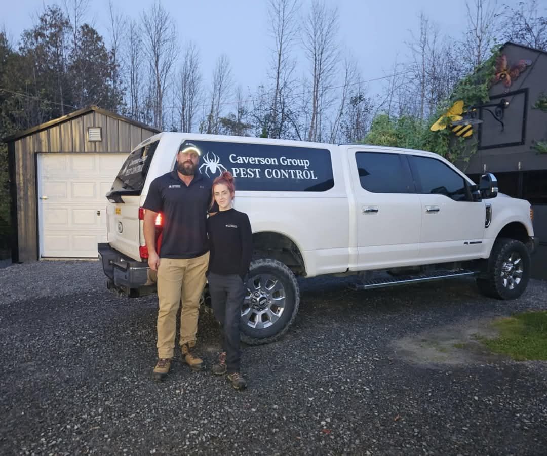 A man and a boy are standing in front of a white truck that says pest control.