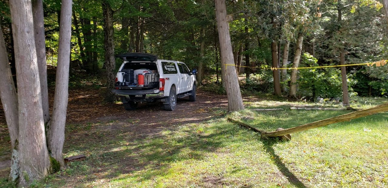 A white truck is parked in the middle of a forest.