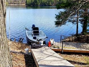 A boat is docked at a dock on the shore of a lake.