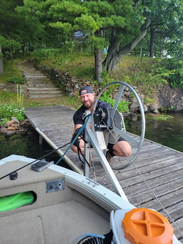 A man is sitting on the steering wheel of a boat on a dock.