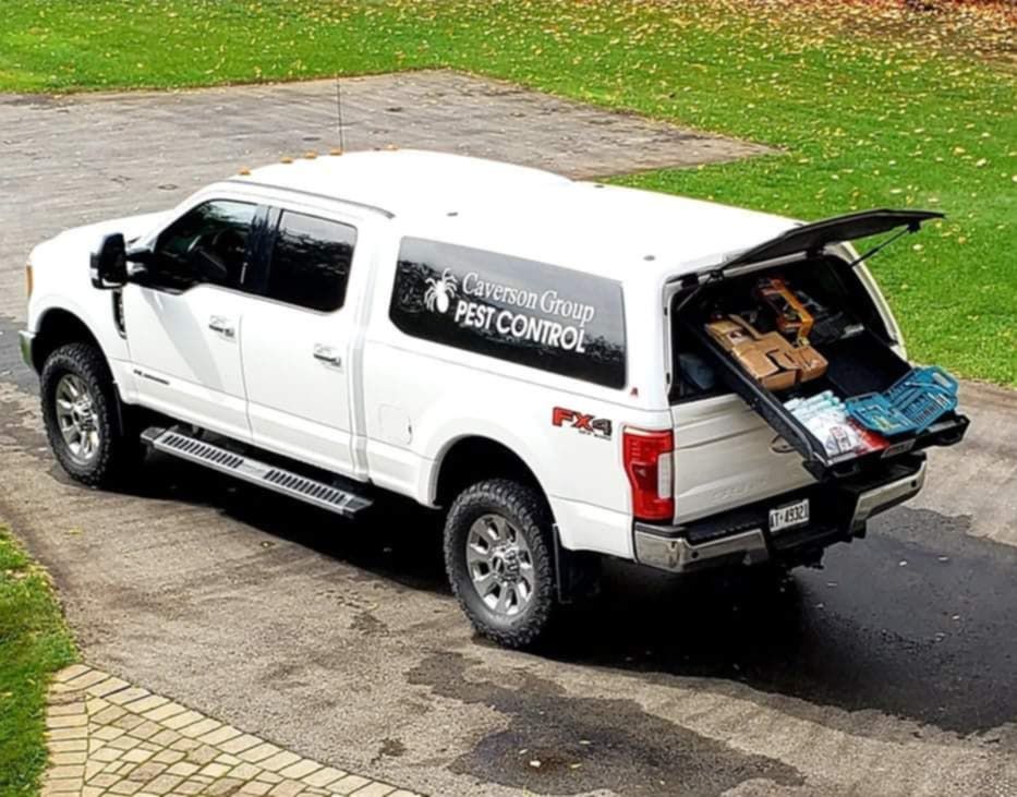 A white truck with the trunk open is parked in a driveway.