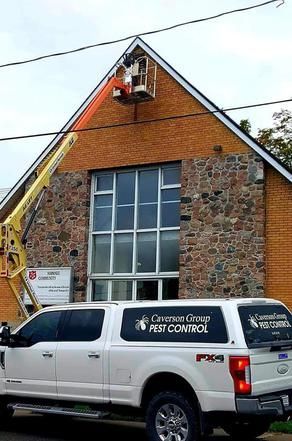 A white truck is parked in front of a brick building completing proofing