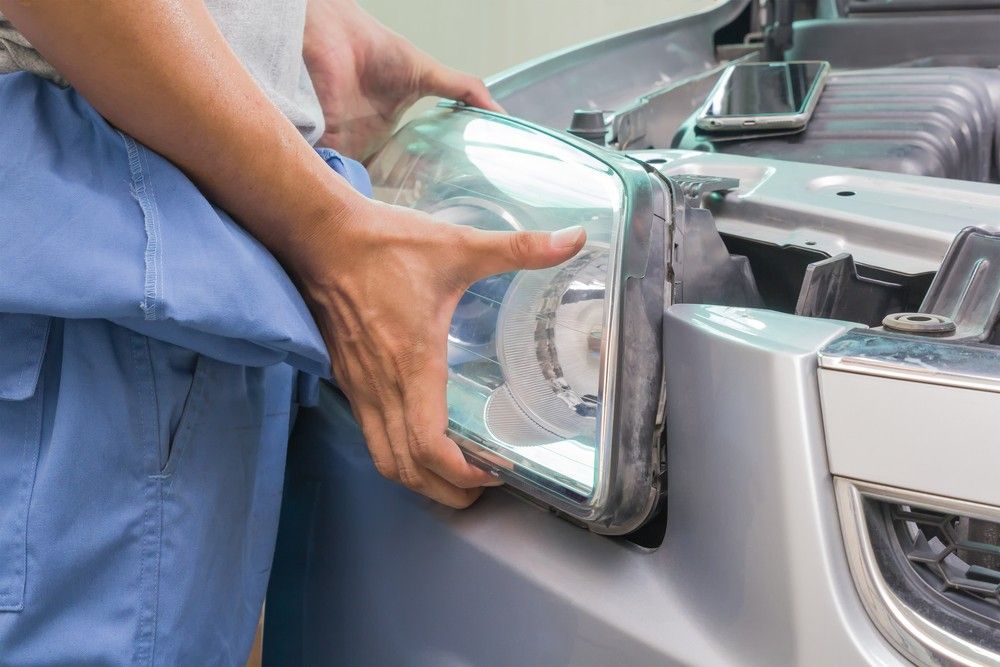 A Man is Fixing the Headlight of a Car — Ravenshoe Auto Electrical In Ravenshoe, QLD