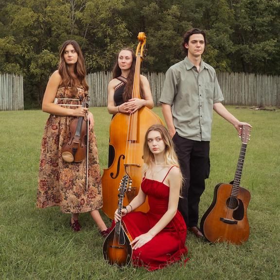 A young man is sitting on a bale of hay.