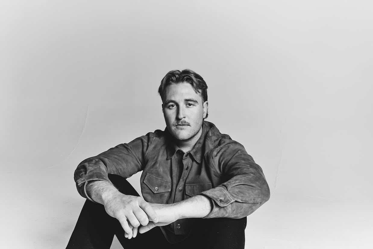 A man is sitting on the floor in a black and white photo.