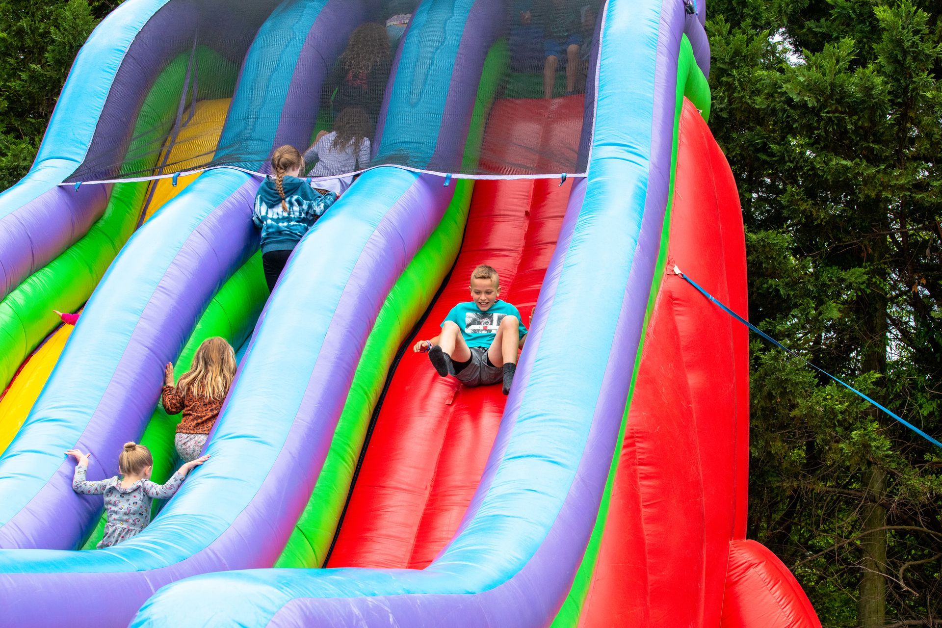 A group of children are riding down a colorful inflatable slide.