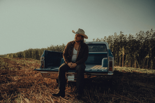 A black and white photo of a young man wearing a daytona hat