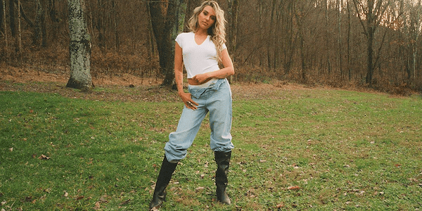 A man wearing a red hat and a white t-shirt is standing with his arms crossed.