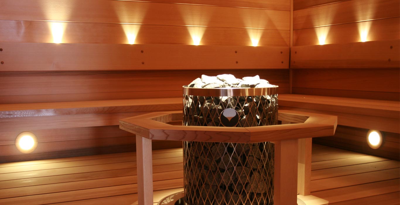 a wooden sauna with a heater in the middle of the room .