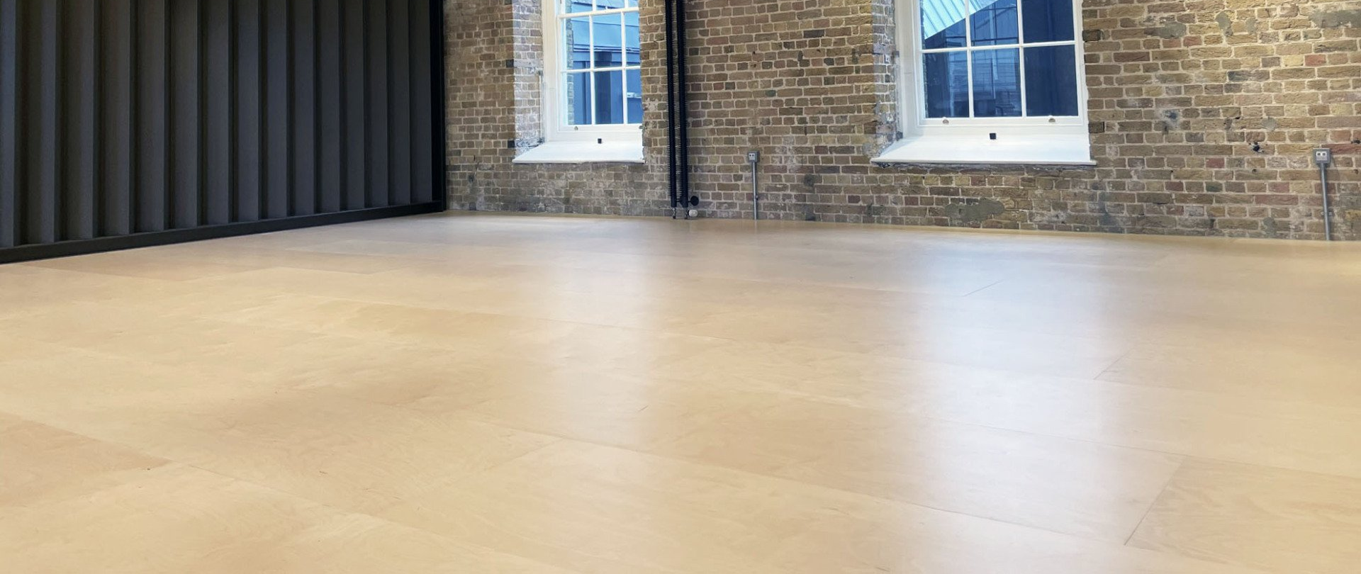 an empty room with two windows and a brick wall