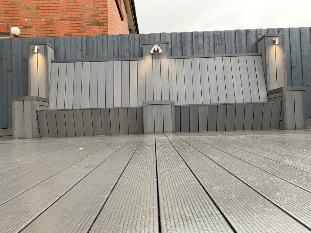 a wooden deck with a bench and a fence in the background .