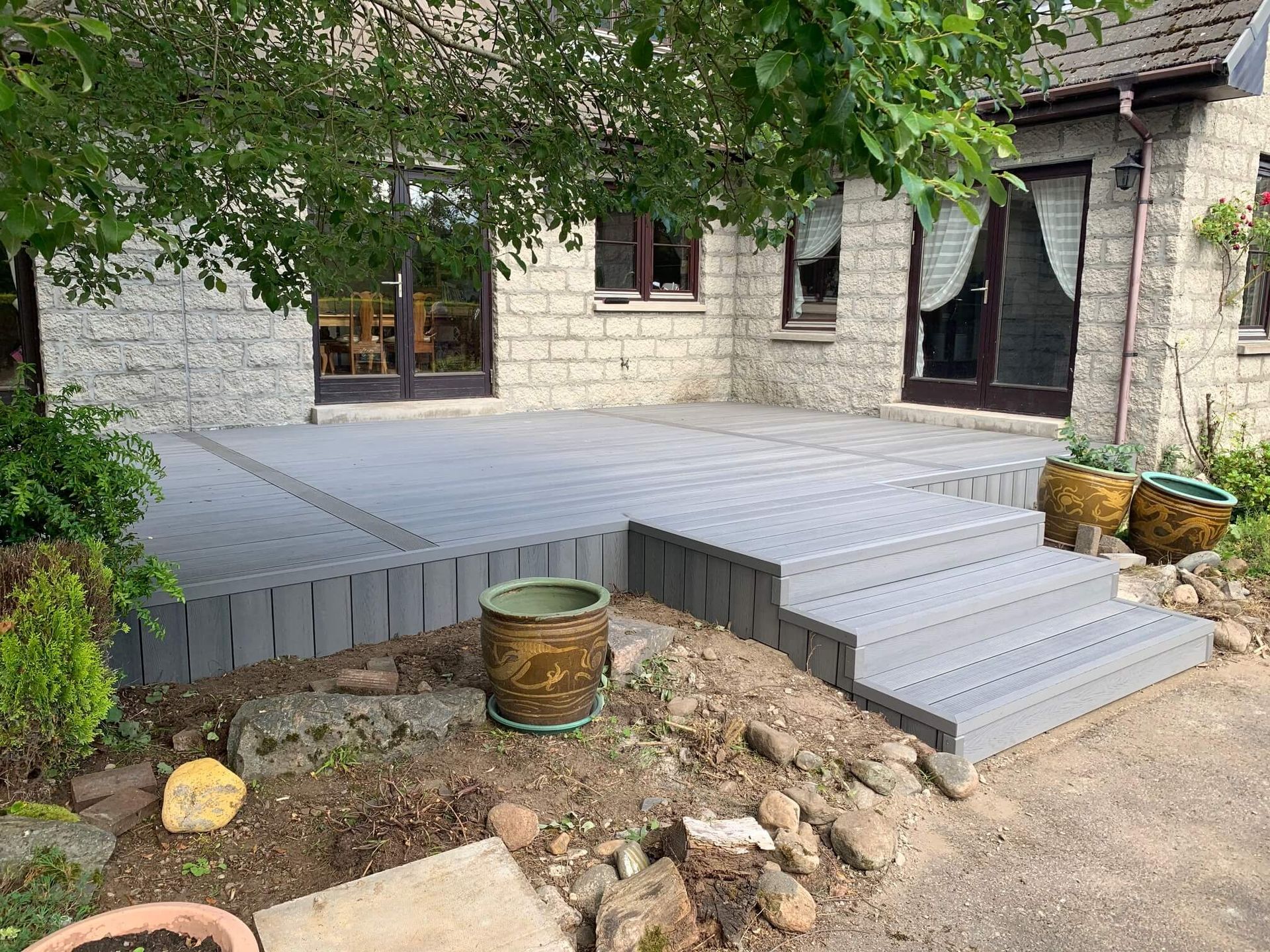 a patio with stairs and potted plants in front of a brick house .