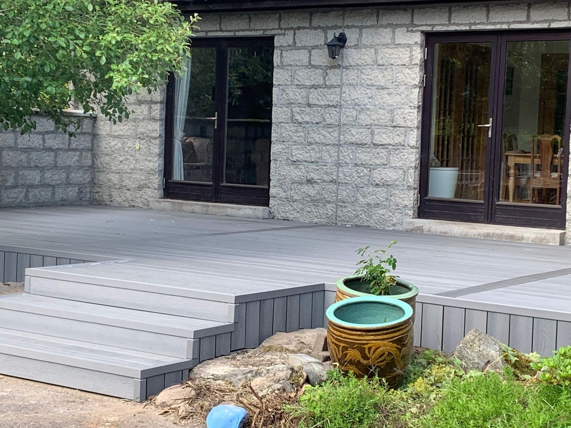 a brick house with a deck and potted plants in front of it