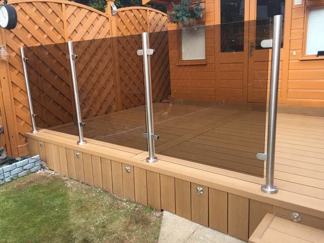 a wooden deck with a glass railing and a wooden fence .