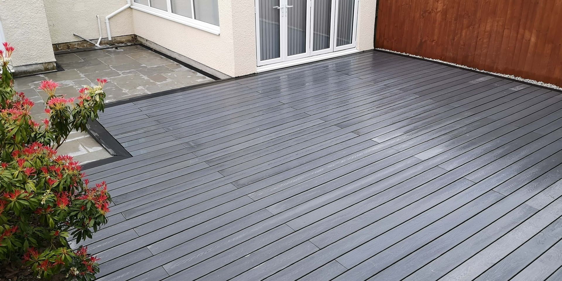 a patio with a gray wooden deck and a wooden fence .
