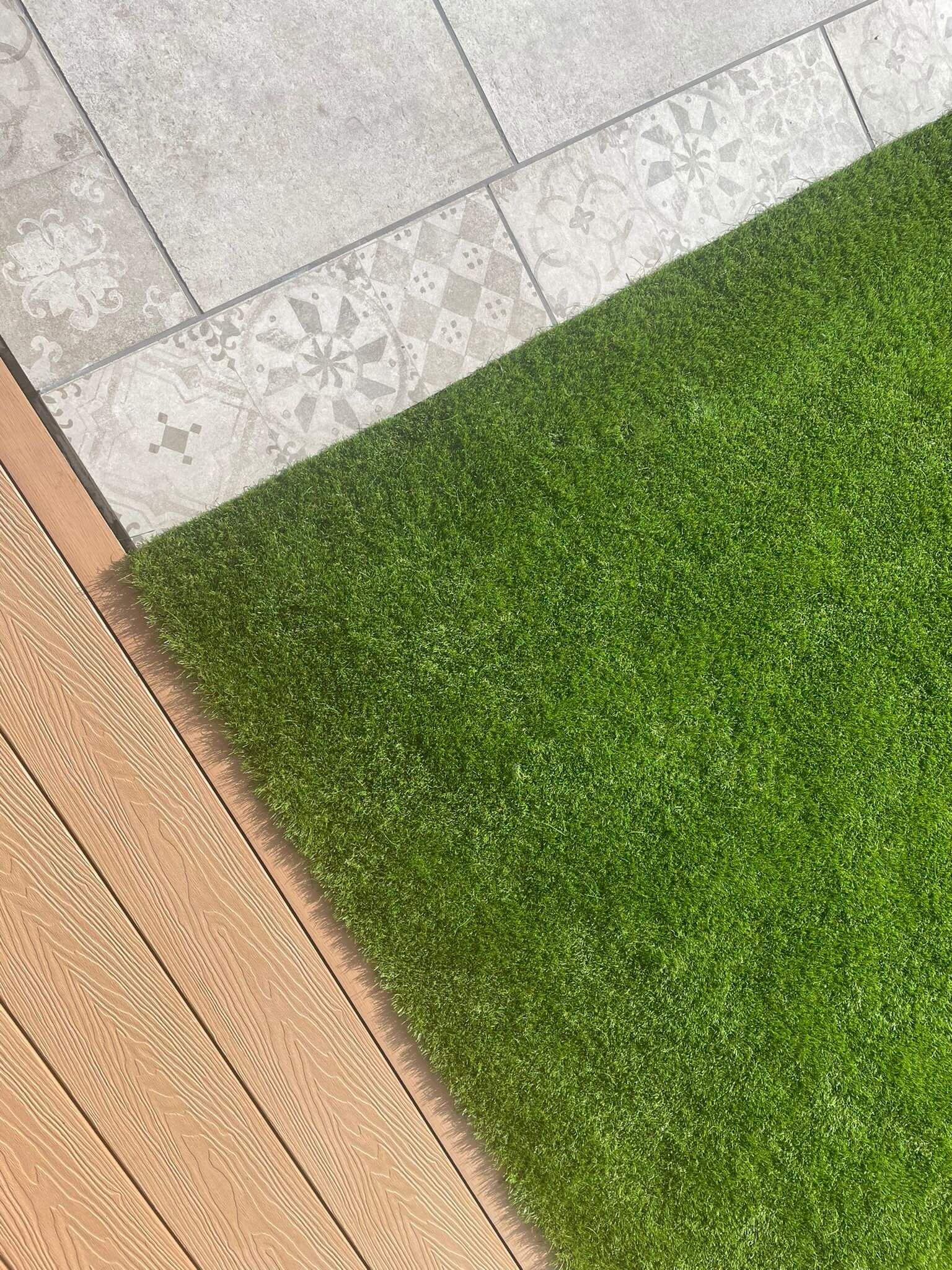 a close up of a lawn next to a wooden deck .