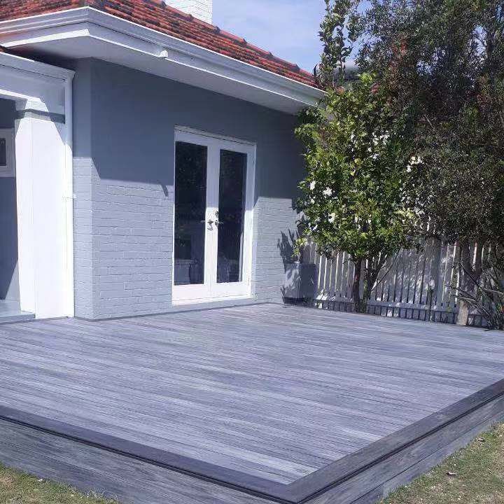 a gray house with a wooden deck in front of it .