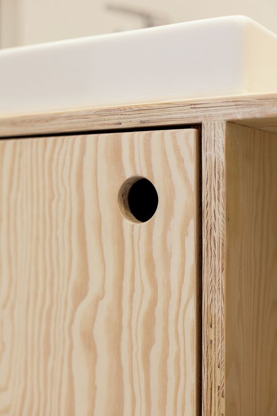 a close up of a wooden cabinet with a white sink in the background .