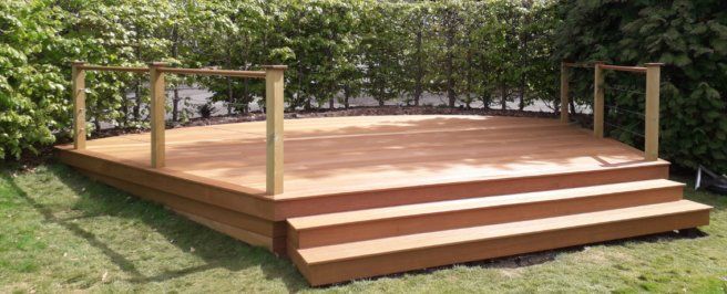 a wooden deck with stairs and a railing in a backyard .