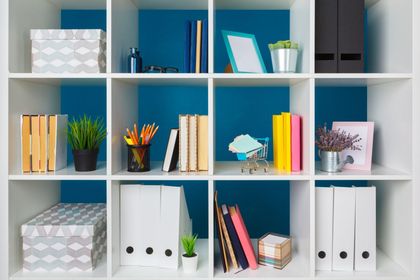 a white shelf filled with books and binders