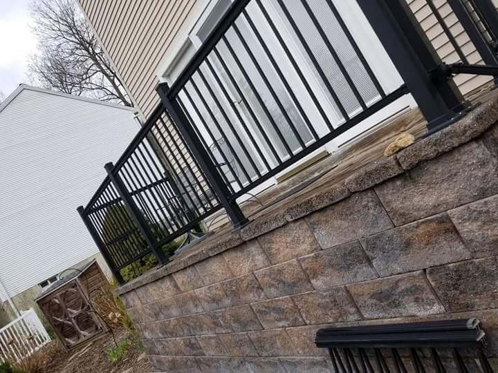 A black railing is sitting on top of a brick wall next to a house.