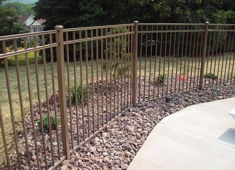 A metal fence surrounds a gravel area in a backyard