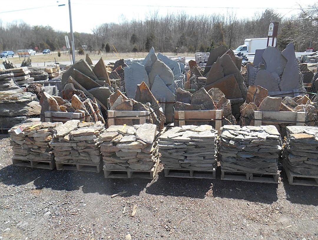 A pile of rocks sitting on top of wooden pallets in a field.