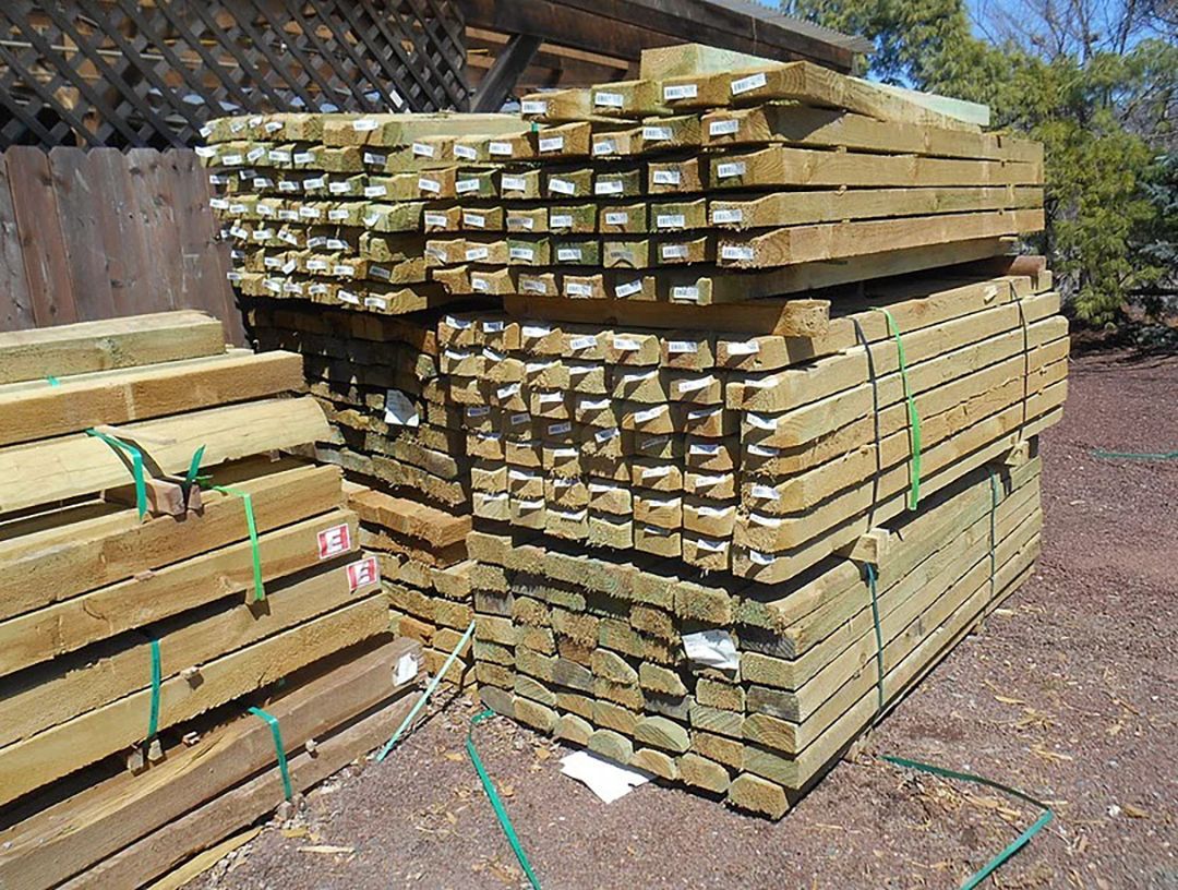 A pile of wooden boards stacked on top of each other on the ground.